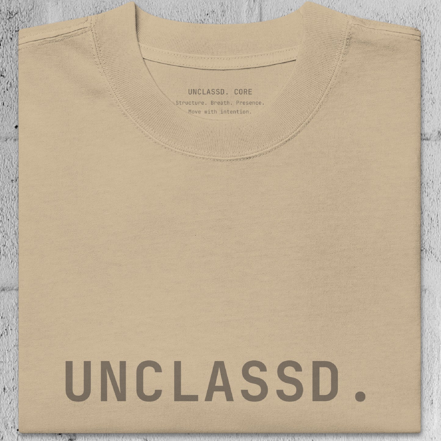 Close-up of faded khaki/beige heavyweight 240gsm cotton texture from the UNCLASSD CORE Oversized Tee, garment-dyed surface.