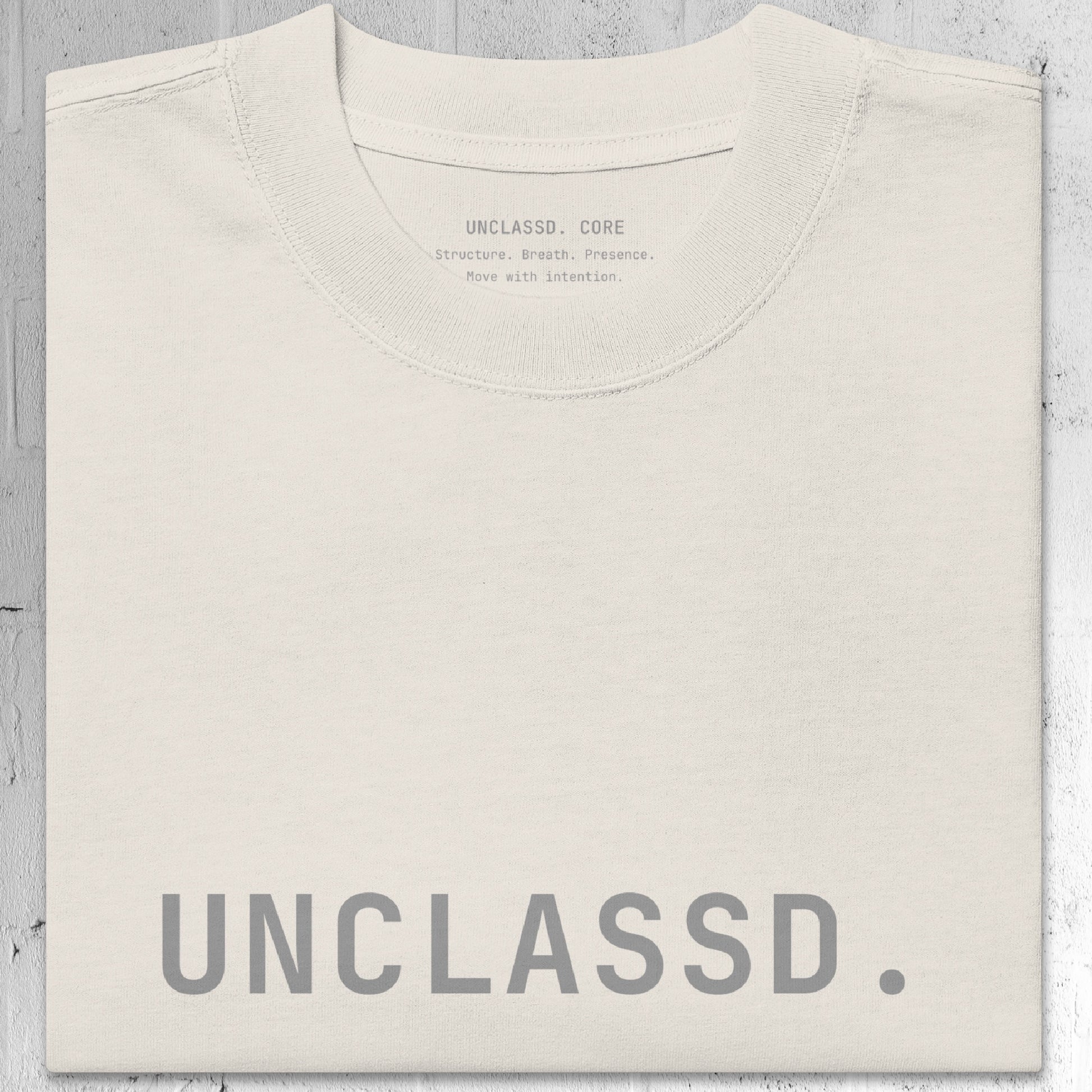 Tonal “UNCLASSD.” chest print detail on the CORE Oversized Tee in Bone color.